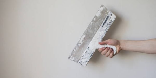 Jinshuo HEC for Wall Putty Skim Coat Working tool, spatula in hand on a light background, work plasterer, painter, to make repairs . Trowel in man's hand on a background of a white wall . Space for text