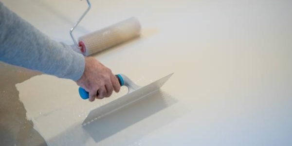 Construction worker plastering a wall using a trowel, during a house renovation Construction worker plastering a wall using a trowel, during a house renovation